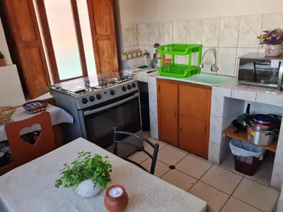 a kitchen with a stove and a sink and a table at Minidepartamento amoblado in Cusco