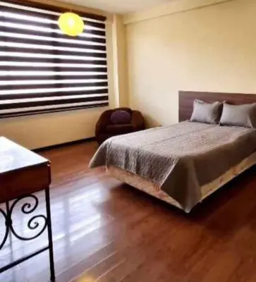 a bedroom with a bed and a chair and a window at chaski apart in Cusco