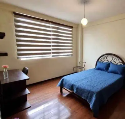 a bedroom with a blue bed and a window at chaski apart in Cusco