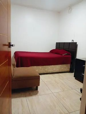 a bedroom with a bed with a red blanket at Lima Colibrí habitaciones in Lima