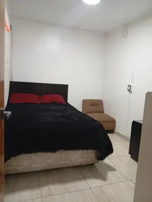 a bedroom with a black bed and a chair at Lima Colibrí habitaciones in Lima