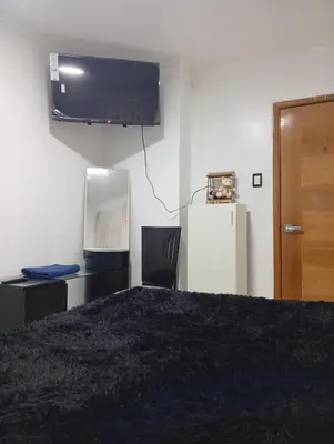 a room with a bed and a tv and a refrigerator at Lima Colibrí habitaciones in Lima