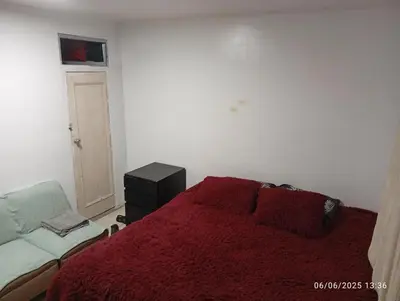 a bedroom with a bed with a red blanket and a chair at Colibrí12 in Lima