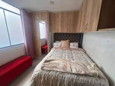 a bedroom with a large bed and a red couch at Departamento Palmeras in Lima