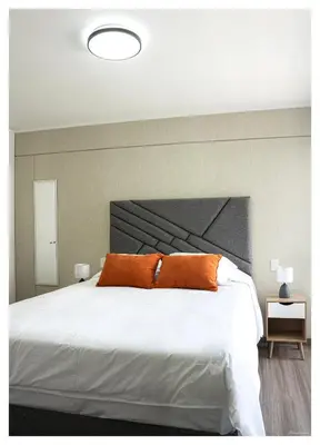 a bedroom with a large white bed with orange pillows at Fantastic New Apartment with Rooftop Pool and Gym in San Isidro in Lima