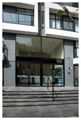 a building with glass doors with a man walking into it at Fantastic New Apartment with Rooftop Pool and Gym in San Isidro in Lima