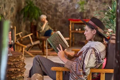 a woman sitting on a bench reading a book at Piedra Wasi Ecolodge Urubamba in Urubamba