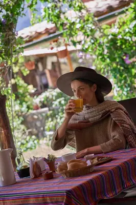 a woman sitting at a table with a glass of juice at Piedra Wasi Ecolodge Urubamba in Urubamba