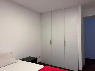 a bedroom with white cabinets and a bed with a red blanket at Villaflores Apartments in Lima