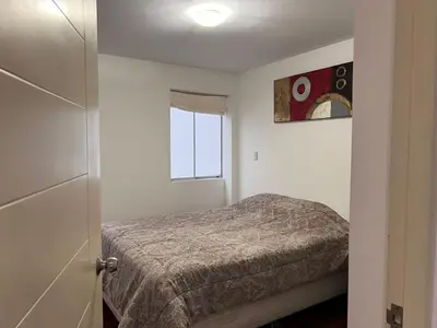 a small bedroom with a bed and a window at Villaflores Apartments in Lima