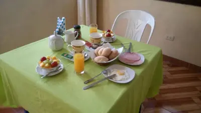 a table with a green table cloth with breakfast foods on it at Hostal Geminis in Ica
