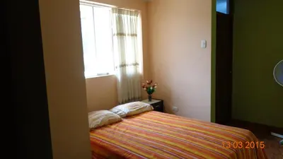 a bedroom with a bed with a window and a vase of flowers at Hostal Geminis in Ica