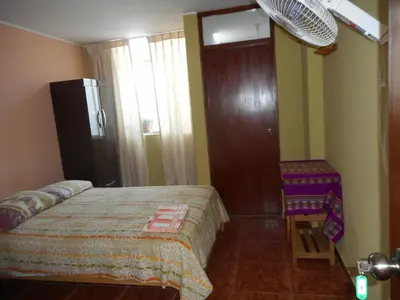 a bedroom with a bed and a door and a chair at Hostal Geminis in Ica