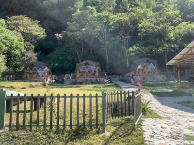 a group of huts in a field with a fence at Salkantay Majestic Domes Eco Lodge in Sahuayacu
