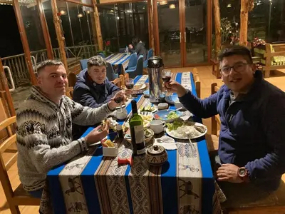 three men sitting at a table drinking wine at Salkantay Majestic Domes Eco Lodge in Sahuayacu