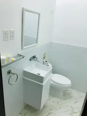 a white bathroom with a toilet and a sink at Larq'a Park Rooms in Lima