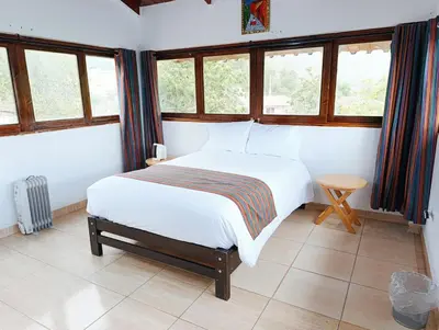 a bedroom with a white bed in a room with windows at Samana House Yanahuara Valle Sagrado in Urubamba