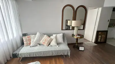 a living room with a couch with pillows and a mirror at Miraflores Apartment w Kingsize Bed in Lima