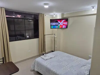 a bedroom with a bed and a tv on the wall at Habitación privada con vista a la calle cerca a la plaza Constitución in Huancayo