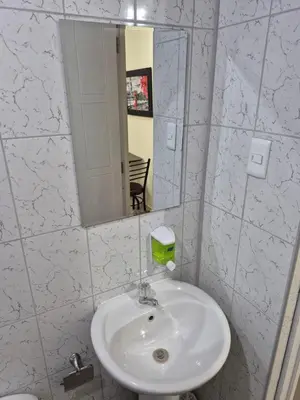 a white bathroom with a sink and a mirror at Habitación privada con vista a la calle cerca a la plaza Constitución in Huancayo