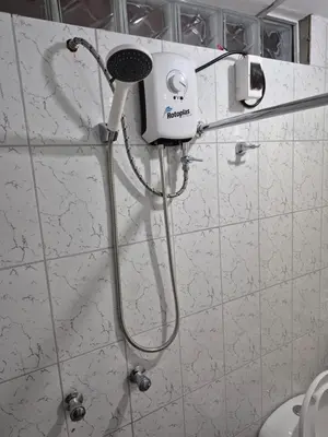 a shower in a bathroom with a blow dryer on the wall at Habitación privada con vista a la calle cerca a la plaza Constitución in Huancayo