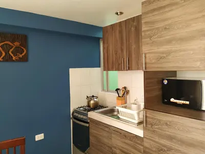 a small kitchen with a sink and a microwave at La Casa de Justi in Huancayo