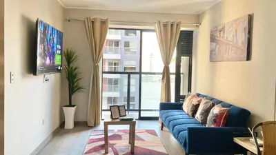 a living room with a blue couch and a window at Departamento exclusivo con vista a la ciudad in Lima
