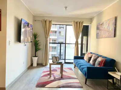 a living room with a blue couch and a window at Departamento exclusivo con vista a la ciudad in Lima