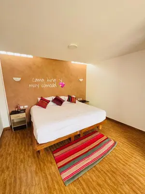 a bedroom with a large white bed with a wooden headboard at Yoga Home in Urubamba