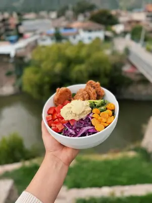 a hand holding a bowl of vegetables and meatballs at Yoga Home in Urubamba