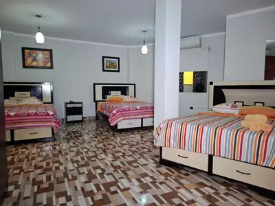 a bedroom with two beds and a wooden floor at Hostal los Faroles in Barranca