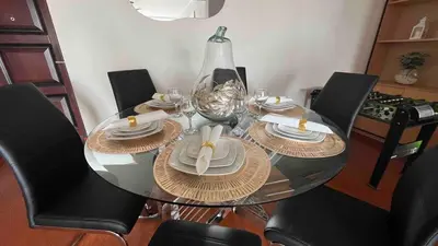 a glass dining room table with black chairs and plates and a bowl at A 15 minutos del aeropuerto cómodo y moderno departamento de 3 habitaciones independientes y 2 baños in Lima