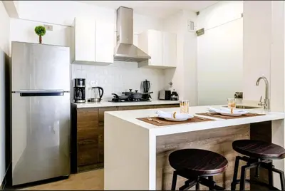 a kitchen with white cabinets and a counter with two stools at Premium Miraflores Stay with Pool and Amenities in Lima