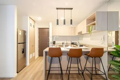 a kitchen with a island with three bar stools at Edificio Los Pinos in Lima