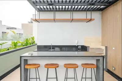 a kitchen with a counter with three bar stools at Edificio Los Pinos in Lima
