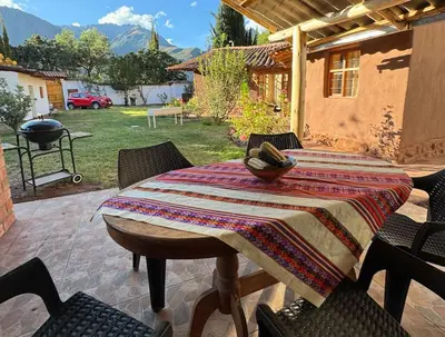 a table with a blanket on a patio with chairs at Urquillos Wasi - Andean Cottage in Urubamba