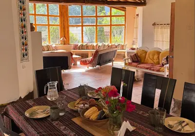 a dining room with a table and a living room at Urquillos Wasi - Andean Cottage in Urubamba