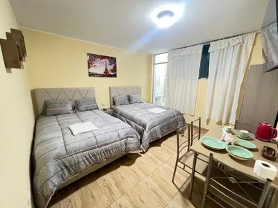 a bedroom with two beds and a table in it at Habitaciones privadas para alojamiento en Ica, Perú in Ica
