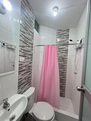a bathroom with a pink shower curtain and a toilet at Habitaciones privadas para alojamiento en Ica, Perú in Ica