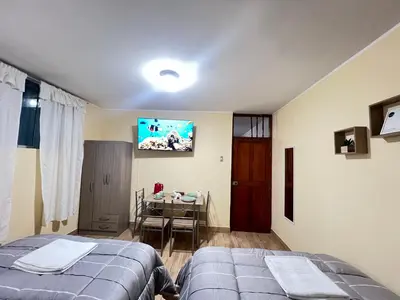 a bedroom with a bed and a table and a tv at Habitaciones privadas para alojamiento en Ica, Perú in Ica