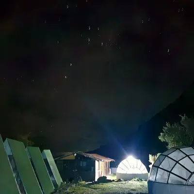 a beam of light shines over two domes at night at Salkantay starcamp in Anta