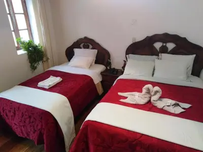 two beds with towels and slippers on them in a room at Imperial Cusco INN in Cusco