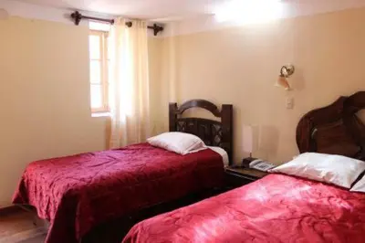 a bedroom with two beds with red sheets and a window at Imperial Cusco INN in Cusco