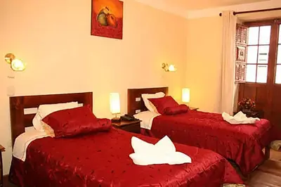 a hotel room with two beds with red sheets at Imperial Cusco INN in Cusco