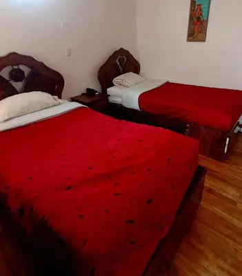 two beds with red sheets in a room at Imperial Cusco INN in Cusco
