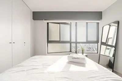 a white bedroom with a large bed and a window at Edificio Olavegoya in Lima