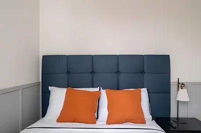 a bed with a blue headboard and orange pillows at Edificio Parque Castilla in Lima