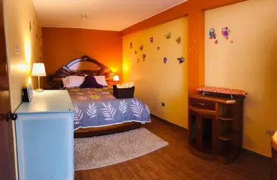 a bedroom with a bed and a table with a night stand at Casa Hilda in Huancayo