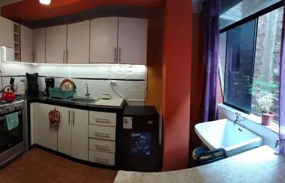 a kitchen with white cabinets and a sink and a window at Casa Hilda in Huancayo