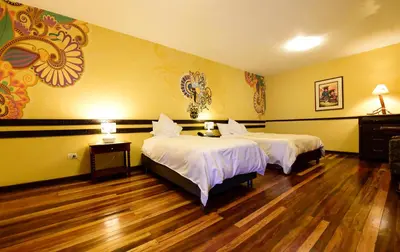 two beds in a room with yellow walls and wooden floors at Yabar Hotel Plaza in Cusco